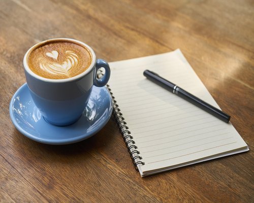 Coffee cup next to an open notebook
